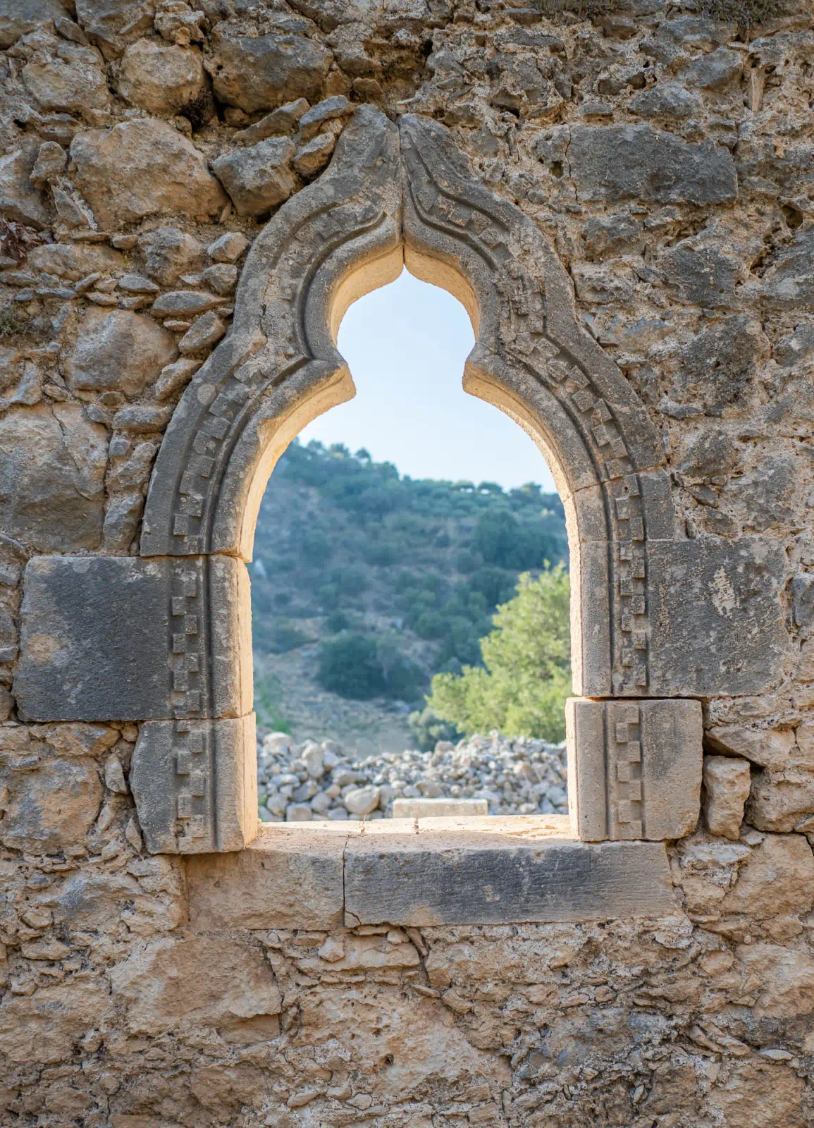 The first window on the south wall of Agios Antonios in Petali. It is in good condition, with all the stones and cornerstones remaining in their original positions. The window is decorated with a pointed arch and a sculpted interior. There is a diagonal crack running through the interior of the window, but it does not affect the structure.