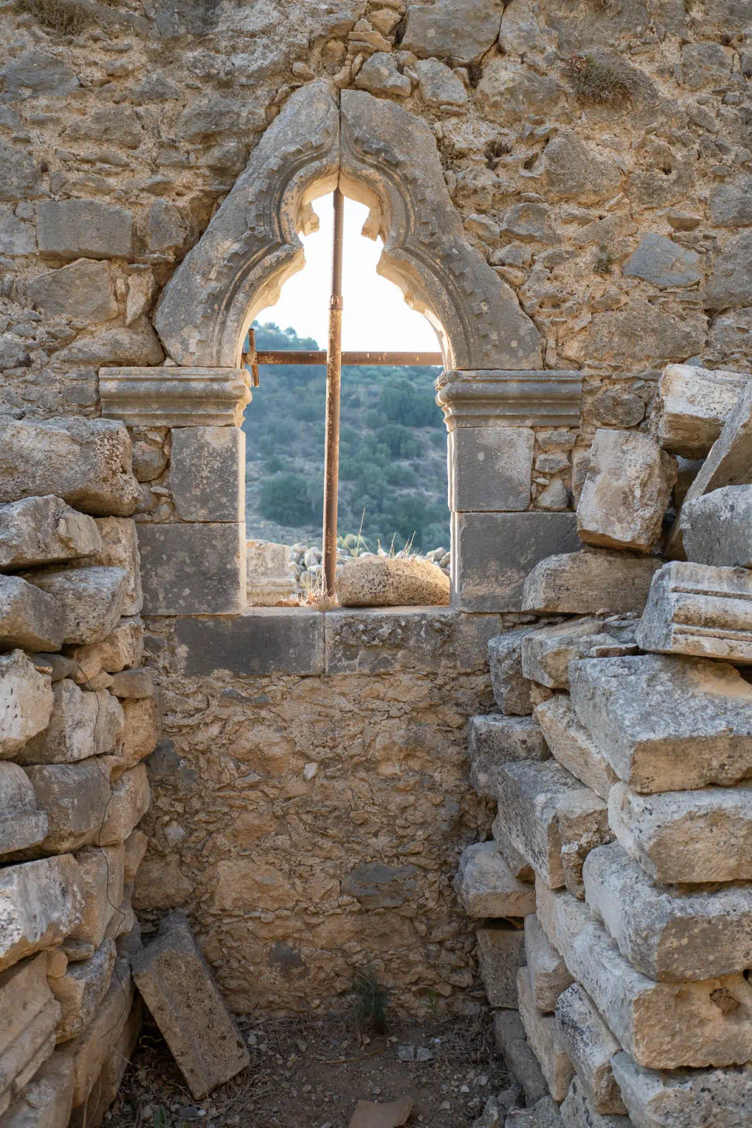 The second window on the south wall of Agios Antonios in Petali church. This window is not in good condition, with half of the lintel, the left cornice, and the right cornerstone missing. The window is decorated with a pointed arch and a sculpted interior. There is a metal scaffolding structure in the window opening for support.